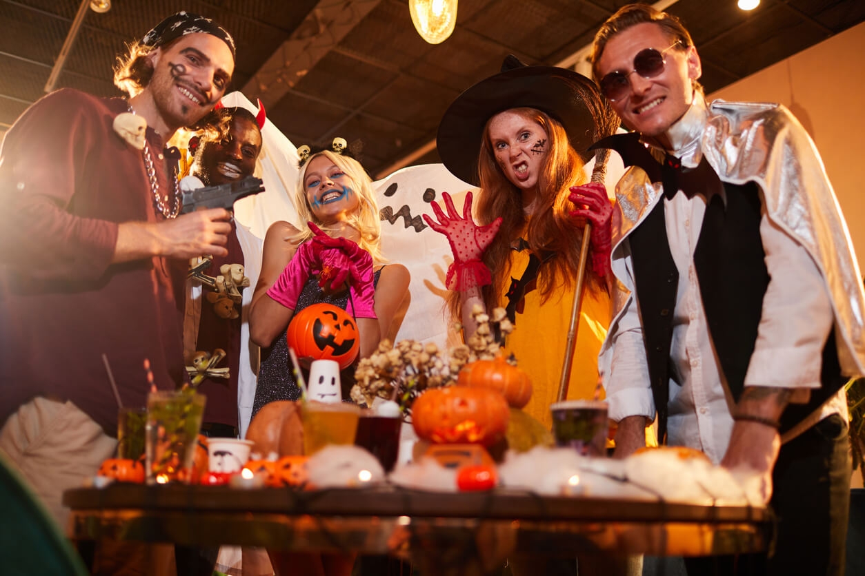 A group of friends gathered around a table, all dressed in different Halloween costumes.